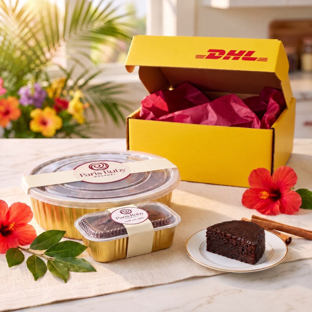 A 1 lb Paris Ruby fruitcake and a half-pound mini in gold pans beside an open yellow DHL Express box
